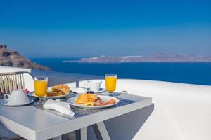 Breakfast time in Santorini in hotel. Luxury mood with fresh omelet and fruits with juice over sea view. Luxurious summer traveling holiday background. Happy relax vibes, couple morning closeup table