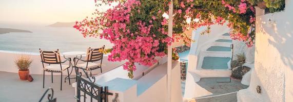 hermosa vista de la caldera y disfrutando del paisaje romántico puesta de sol mar egeo, santorini. vacaciones de viaje en pareja, destino de luna de miel. romance con flores, mesa dos sillas y vista al mar. vacaciones de lujo foto