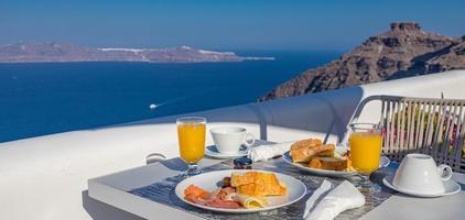 Breakfast time in Santorini in hotel. Luxury mood with fresh omelet and fruits with juice over sea view. Luxurious summer traveling holiday background. Happy relax vibes, couple morning closeup table photo