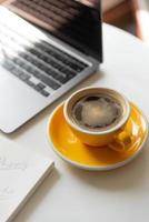 yellow cup of coffee on workspace on table near laptop flat lay of work place of freela photo