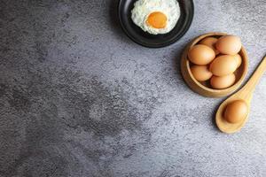 huevos fritos en una sartén y huevos frescos en la mesa foto