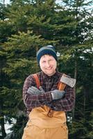 retrato de un hombre leñador con un hacha en las manos sobre un fondo de bosque y árboles foto