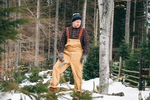 retrato de un hombre leñador con un hacha en las manos sobre un fondo de bosque y árboles foto