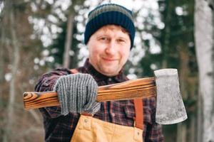 Portrait of a man lumberjack with an ax in his hands on a background of forest and trees photo