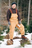 retrato de un hombre leñador con un hacha en las manos sobre un fondo de bosque y árboles foto