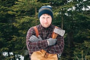 retrato de un hombre leñador con un hacha en las manos sobre un fondo de bosque y árboles foto