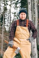 Portrait of a man lumberjack with an ax in his hands on a background of forest and trees photo