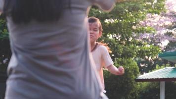 Little daughter ran to her mother and hugged her in the park in autumn. Cute kid is having fun with mommy in playground video