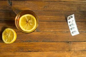 Top view, a cup of tea with lemon and cold pills on wooden background, copyspace. photo