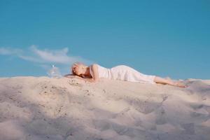 blonde woman in the desert with goldfish in her hands photo