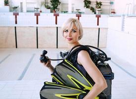 young blonde woman with diving equipment in empty swimming pool. Education, hobby concept photo