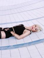 young woman in black underwear and stockings alone in the empty swimming pool photo