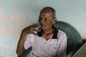 Close up portrait of Asian Javanese old man with a cigarette in his hand photo