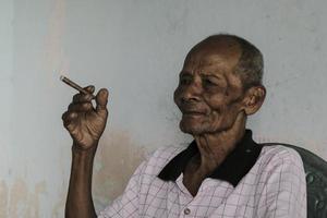 Close up portrait of Asian Javanese old man with a cigarette in his hand photo