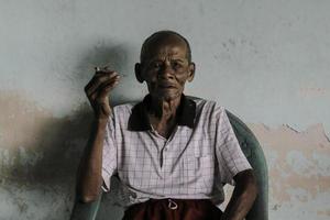 retrato de cerca de un anciano javanés asiático con un cigarrillo en la mano foto