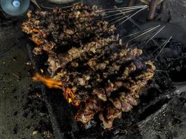 Goat satay on red fire grilling by people. traditional Indonesian food made from mutton. photo