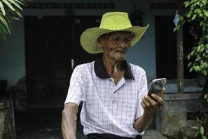 A portrait of Indonesian old grandpa watch screen on smartphone. photo