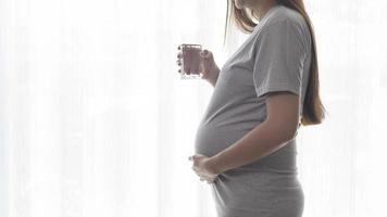 Young pregnant woman drinking water at home, healthcare and pregnancy care concept photo