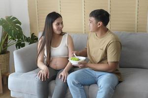 mujer joven embarazada con ensalada en casa, atención médica y atención del embarazo foto