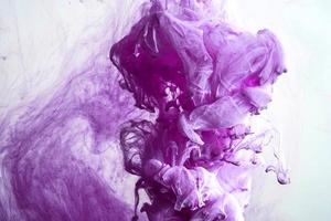 gota de tinta de color púrpura en el agua, tinta arremolinándose. imagen de abstracción para referencia de fondo o color. foto