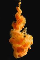 Orange ink drop in clear water and black background. abstract image for background or color reference. photo