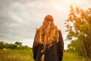 una mujer con el pelo largo se para de espaldas al atardecer foto