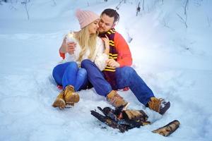 Happy couple in winter in the forest by the fire with sparklers photo