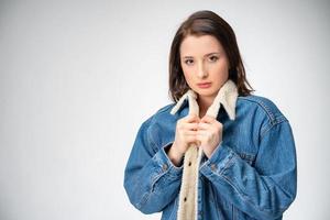 hermosa mujer joven en chaqueta de denim posando sobre fondo blanco foto