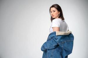 beautiful young woman in denim jacket posing on white background photo