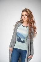 mujer de moda posando sobre fondo blanco, ropa elegante jeans y camiseta con chaqueta de punto foto