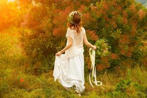 hermosa mujer en un campo con flores al atardecer foto