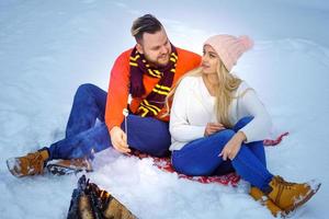 happy couple man and woman in winter in the forest fry marshmallows on the fire photo