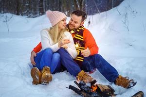 Happy couple in winter in the forest by the fire with sparklers photo