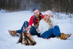 a young couple sits near a campfire photo