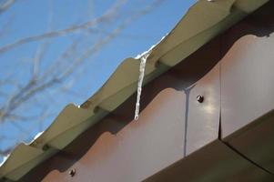 Icicles of ice hang on the structure of the roof of the house photo