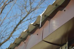 Icicles of ice hang on the structure of the roof of the house photo