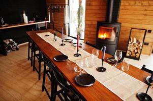 Table with paltes and candies in modern wooden house with fireplace. photo