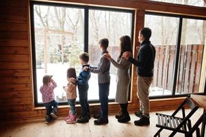Family with four kids in modern wooden house against large window. photo