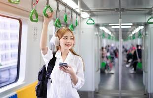 Image of young Asian woman using smartphone on the metro photo