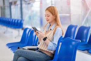 Young Asian woman working while waiting for the train at the train station photo