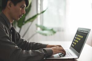A man is typing on a laptop computer photo