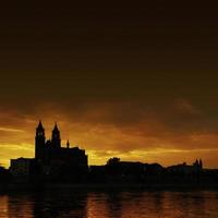 Silhouette of a medieval castle at beautiful bloody sunset at historical downtown of Magdeburg, old town, Elbe river and Magnificent Cathedral, Germany. photo