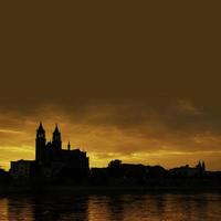 Silhouette of a medieval castle at beautiful bloody sunset at historical downtown of Magdeburg, old town, Elbe river and Magnificent Cathedral, Germany. photo