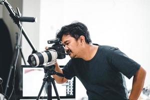 Male photographer taking pictures with his camera and tripod with a monitor and light stand in the background photo