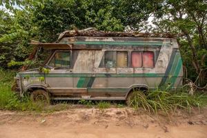 abandonar la vieja furgoneta oxidada desgastada a la izquierda al lado de un camino de tierra en una zona remota de brasil foto
