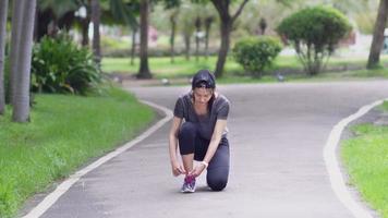 mujer asiática corriendo atando cordones de zapatos para correr antes de entrenar video