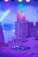 Festive table decorated with composition of candles and silver candlesticks in colored light in the banquet hall. Table newlyweds in the banquet area on wedding party. photo