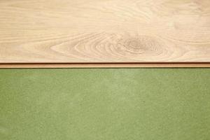 Installing wooden laminate or parquet floor in room over green base. assembling panels quickly and easily - affordable flooring. laying laminate flooring at home photo
