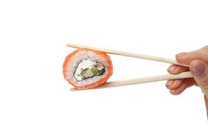 mano femenina sosteniendo rollo de sushi con palillos sobre fondo blanco puro. foto