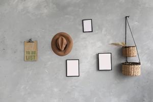 Modern scandinavian home interior with mock up photo frames, wicker baskets for houseplants ,list to do, brown hat on gray wall background. Stylish home decor. Template. Ready to use.